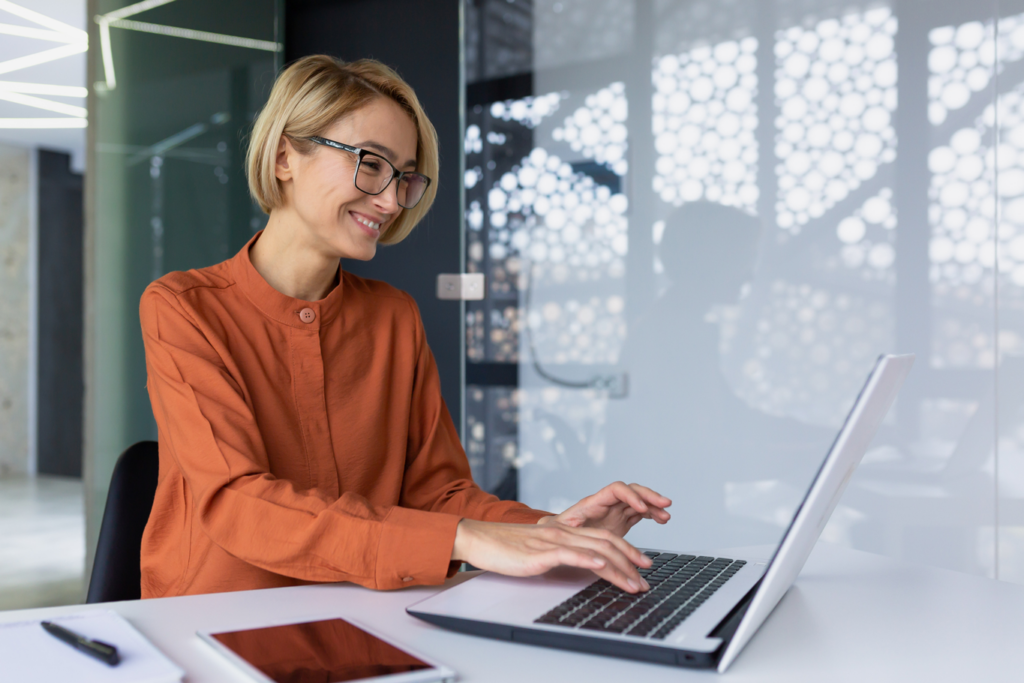 Professional business woman smiling whilst using computer for work