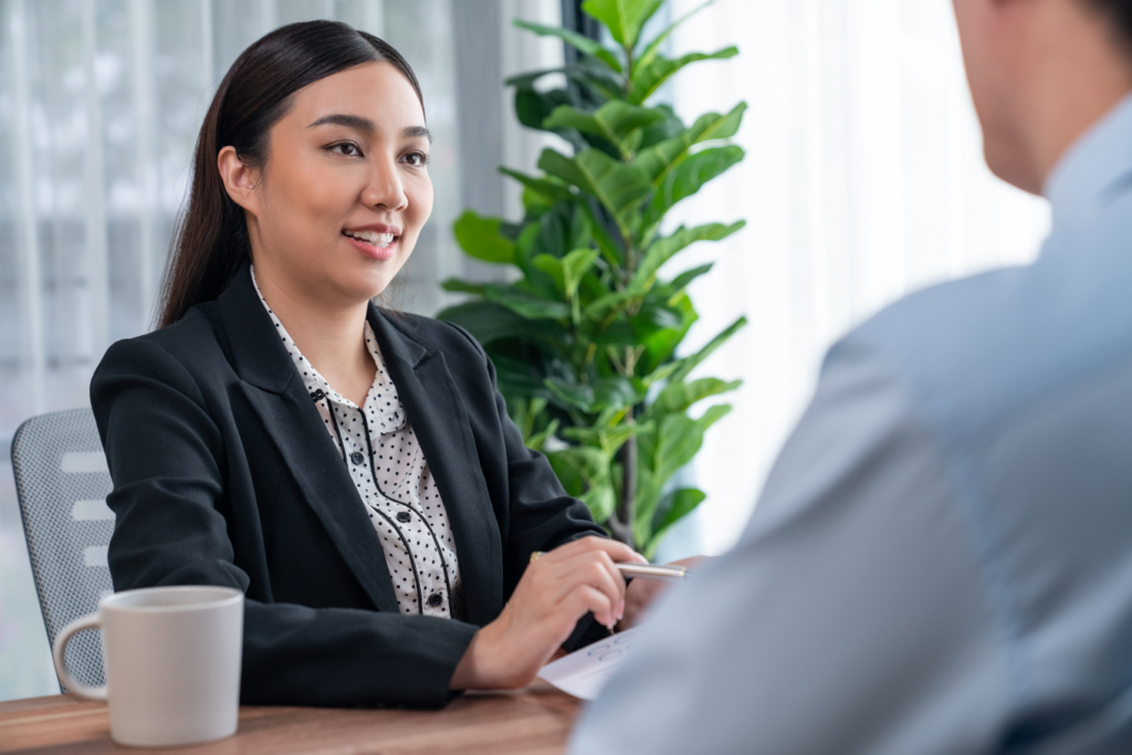 Corporate woman discussing review findings with man with coffee in modern office with plant