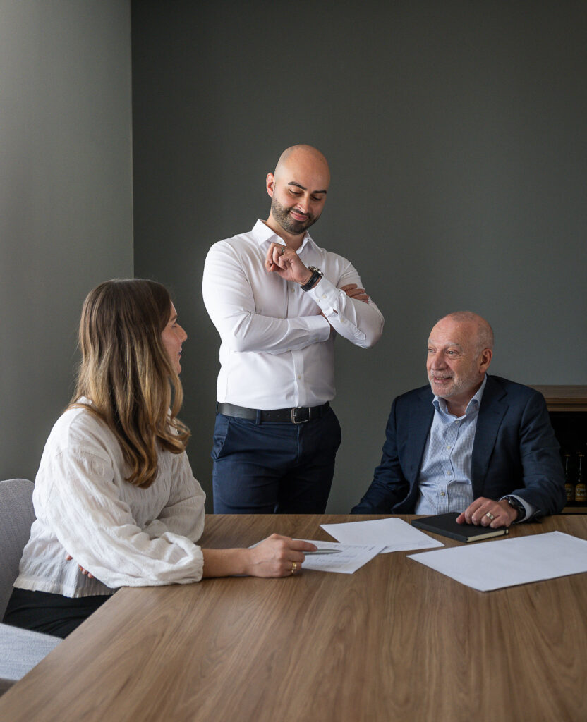 three advisors in a meeting room at a table with papers on it